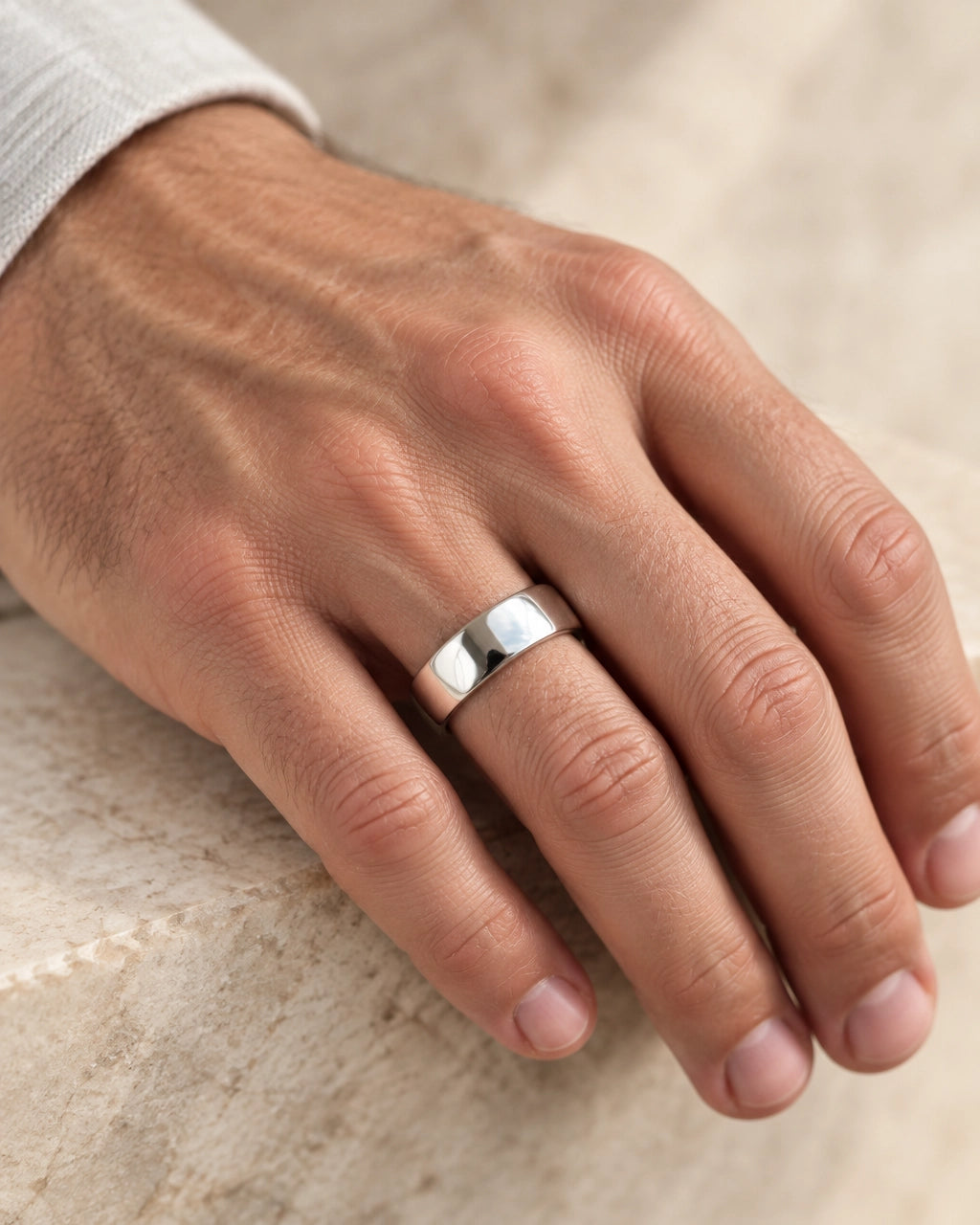 A classic sterling silver band worn on a relaxed hand against a soft neutral background